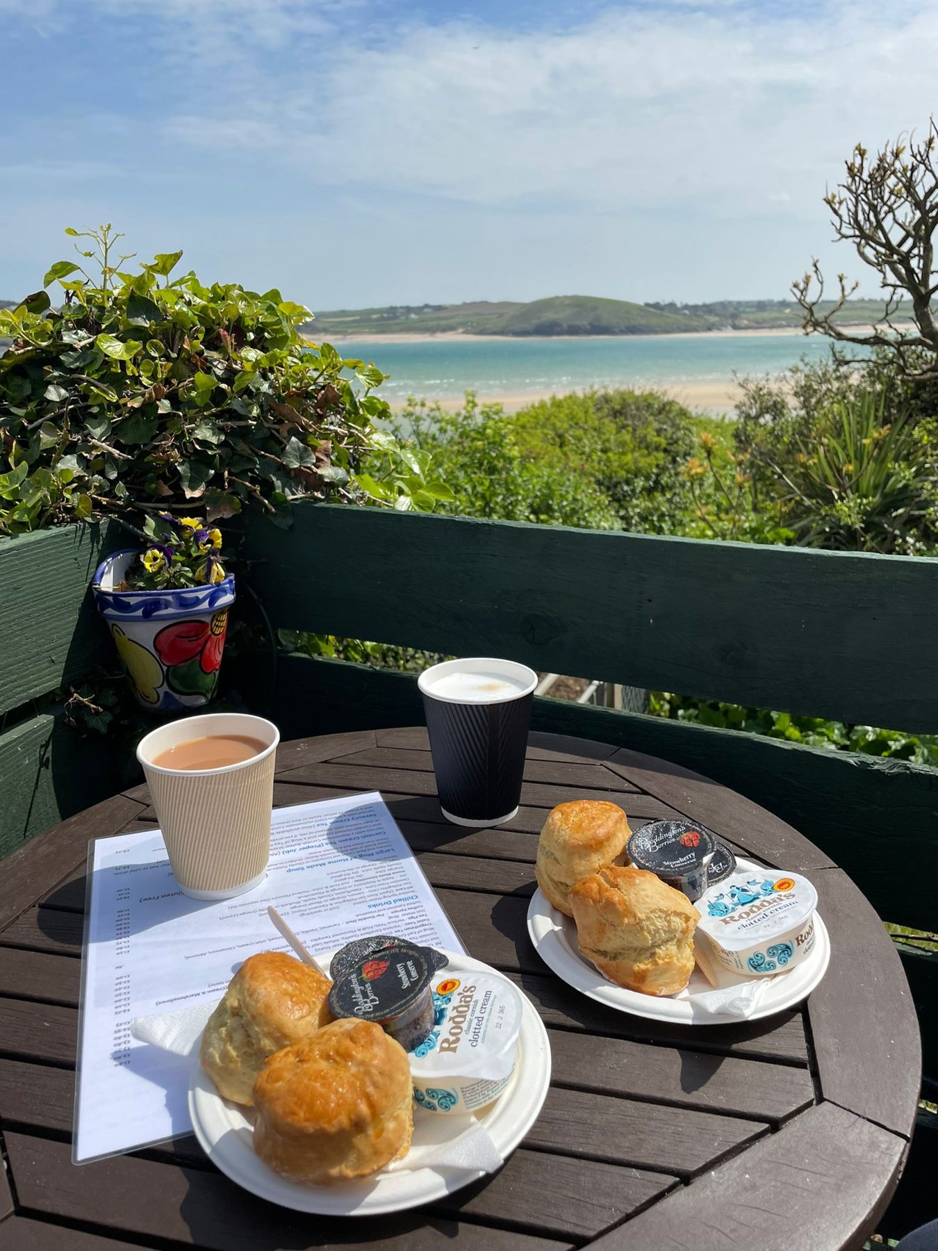 Coffees and scones on a terrace table, with the estuary behind